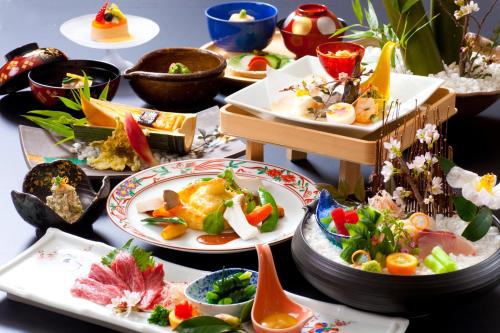 a table topped with plates of food and bowls at Kikunan Onsen Yubel Hotel in Kumamoto