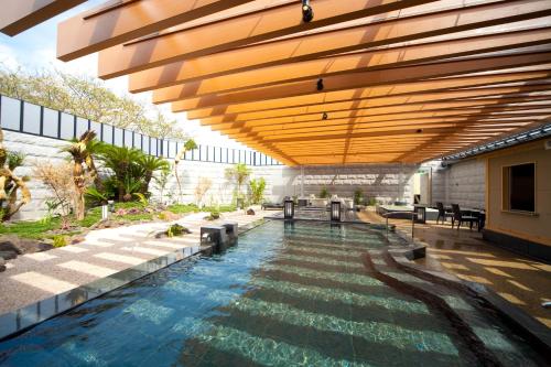 a swimming pool in a building with a wooden ceiling at Kikunan Onsen Yubel Hotel in Kumamoto