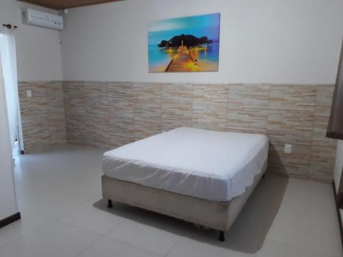 a bedroom with a bed in a room with a brick wall at Duplex com vista do mar! in Itapema