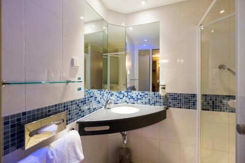 a bathroom with a sink and a glass shower at Holiday Inn Express Gütersloh, an IHG Hotel in Gütersloh
