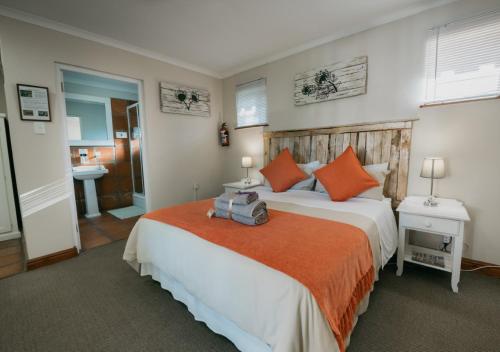 a bedroom with a large bed with orange pillows at The Village Lodge in Stormsrivier
