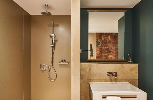 a bathroom with a shower and a sink and a mirror at Hotel Indigo Dresden - Wettiner Platz by IHG in Dresden
