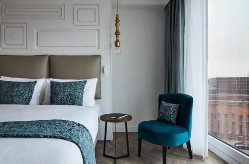 a bedroom with a bed and a chair and a window at Hotel Indigo Dresden - Wettiner Platz by IHG in Dresden