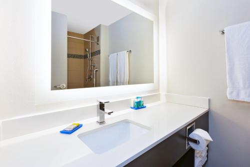 a white bathroom with a sink and a mirror at Holiday Inn Express Winnipeg Airport - Polo Park, an IHG Hotel in Winnipeg