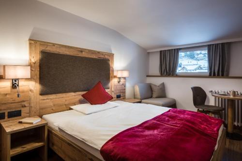 una camera da letto con un grande letto con una coperta rossa di Charme Hotel Uridl a Santa Cristina in Val Gardena