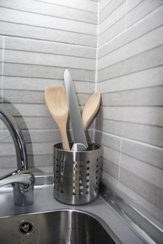 a metal container with wooden utensils in it next to a sink at Vielha Centro Estudio in Vielha