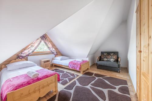 a attic bedroom with two beds and a chair at Góralski Dworek in Czarna Góra