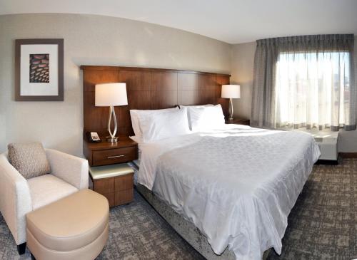 a hotel room with a large bed and a chair at Staybridge Suites - Red Deer North by IHG in Red Deer