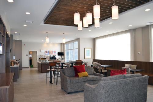 a lobby with chairs and tables and a bar at Staybridge Suites - Red Deer North by IHG in Red Deer