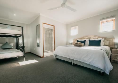 a bedroom with two beds and a ceiling fan at The Village Lodge in Stormsrivier