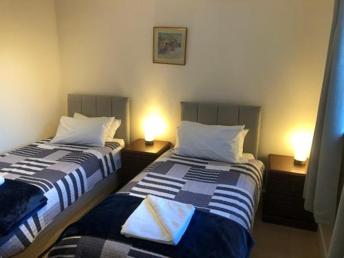 two beds in a room with two lamps on tables at Broadsea in Inverurie