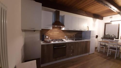 a kitchen with white cabinets and a stove top oven at Locanda del Sasso Rooms in Crodo