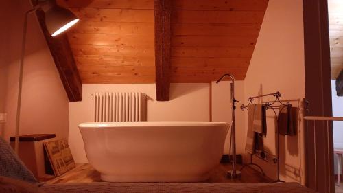 uma grande banheira branca numa casa de banho com tectos em madeira em Locanda del Sasso Rooms em Crodo