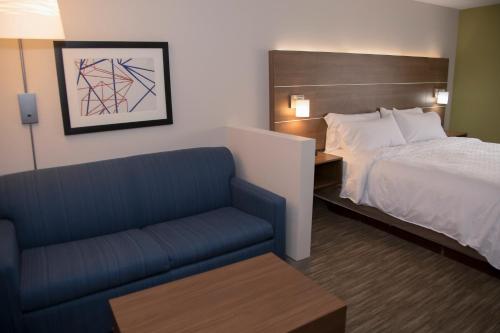 a hotel room with a bed and a blue couch at Holiday Inn Express & Suites Colorado Springs North by IHG in Colorado Springs