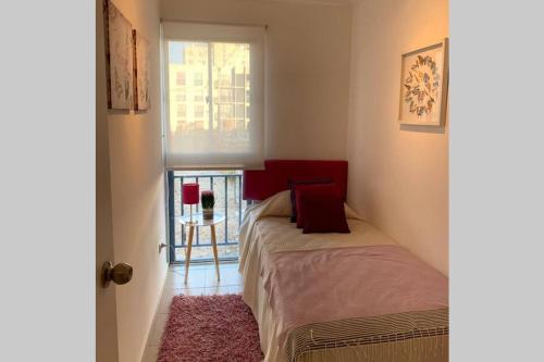 1 dormitorio con 1 cama con cabecero rojo y ventana en Apart Mejillones - Dpto 22 en Mejillones