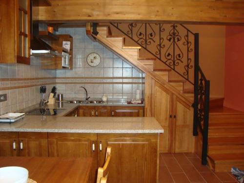 una cocina con armarios de madera y una escalera de caracol en Apartamentos Rurales Posada de las Hoces, en Bustiello de Paredes