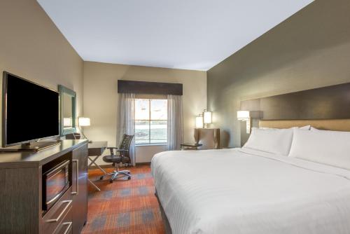 a hotel room with a bed and a flat screen tv at Holiday Inn Express Shawnee by IHG in Shawnee