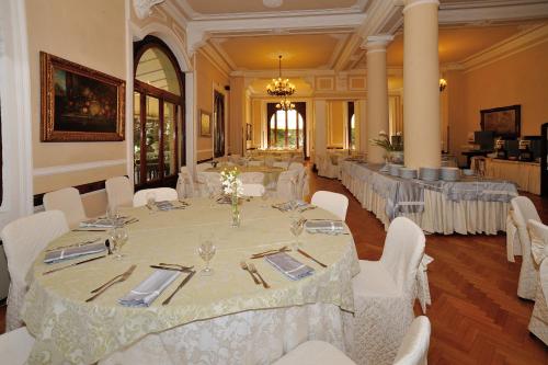 a banquet hall with white tables and white chairs at Grand Hotel Tettuccio in Montecatini Terme