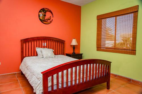 1 dormitorio con paredes de color naranja, 1 cama y ventana en Bella Vista 6, en Puerto Peñasco