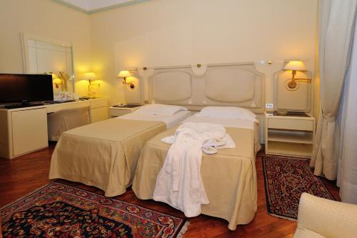 a hotel room with two beds and a television at Grand Hotel Tettuccio in Montecatini Terme