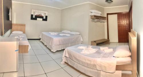 a hospital room with two beds and a refrigerator at Pousada Bonanza in Arraial do Cabo