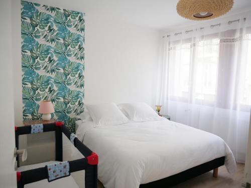 sypialnia z białym łóżkiem i tapetą w kwiaty w obiekcie Superbe appartement en centre ville avec terrasse w mieście Thonon-les-Bains