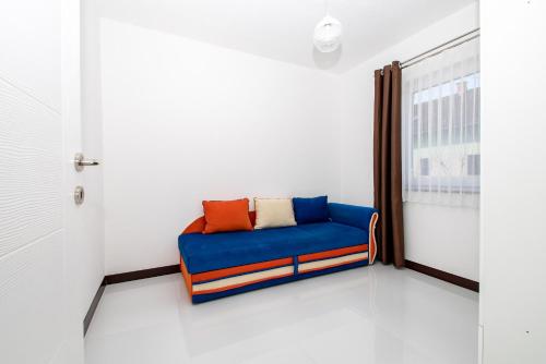 a blue couch in a room with a window at Hazam Apartmani in Sanski most