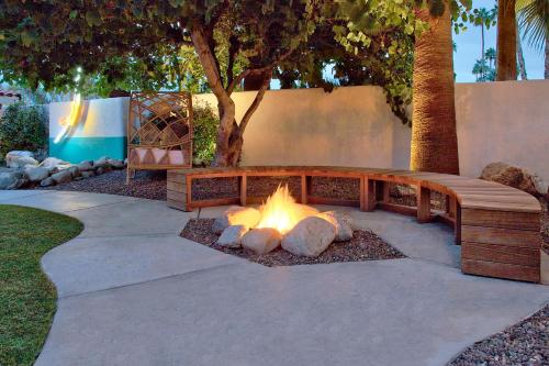 a fire pit in a garden with a wooden bench at Dive Palm Springs in Palm Springs