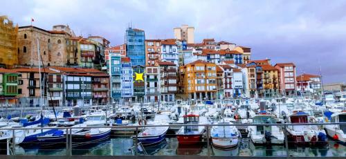 a group of boats docked in a harbor with buildings at Andra Mari Portua in Bermeo
