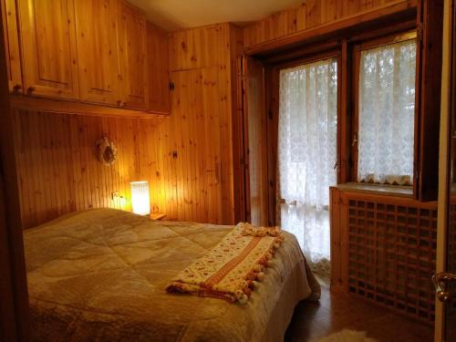 a bedroom with a bed with wooden walls and windows at Pescocostanzo Centro in Pescocostanzo