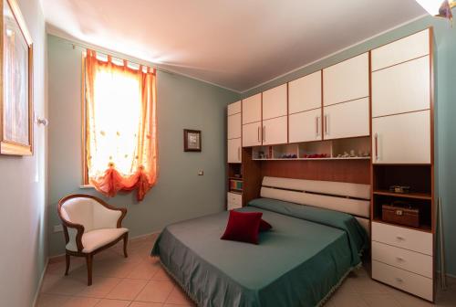 a bedroom with a bed and a chair and a window at Arcobaleno Apartment in Fondi