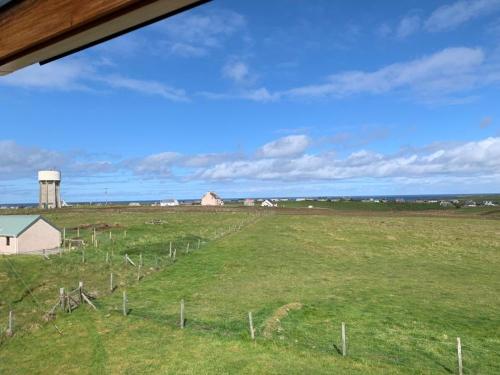 a fence in a field with a farm in the background at 18 Cross Skigesrta Road in Swanibost
