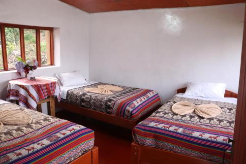 a room with three beds and a table with a window at Llactapata Lodge overlooking Machu Picchu - camping - restaurant in Salcantay