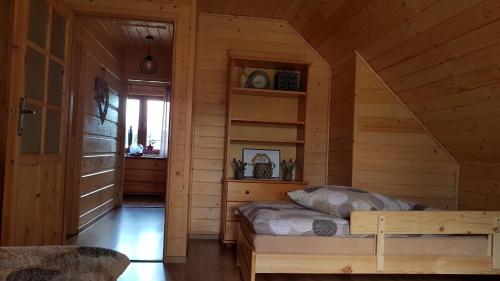 a bedroom with a bed in a wooden cabin at Agroturystyka "Domek pod Praszywką" in Rycerka Górna