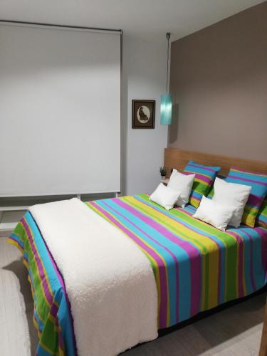 sypialnia z dużym łóżkiem z kolorową pościelą i poduszkami w obiekcie The Little House Sir w mieście Avila