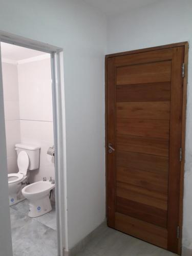 a bathroom with a toilet and a wooden door at MONOAMBIENTE CON COCHERA Y PATIO in Rosario