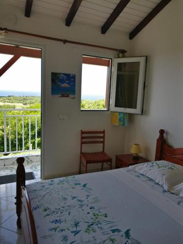 a bedroom with a bed and a balcony at Location Bellevue - Pomme Cannelle in Saint-Louis