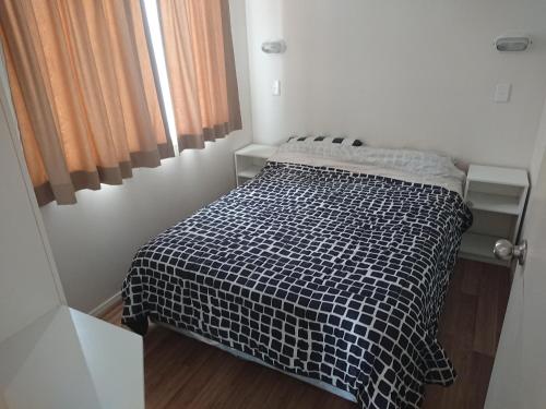 a small bedroom with a bed with a black and white blanket at Caracourt caravan park in Singleton