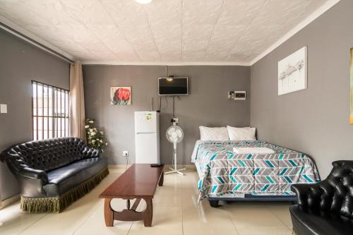 una camera da letto con un letto, un divano e una sedia di Hasate Guest House 10 Florence street Oakdale Belliville 7530 cape town south African a Città del Capo