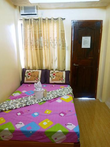 a bedroom with a bed with a purple comforter and a door at Aquing's Place in El Nido