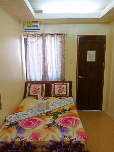 a small bedroom with a bed with flowers on it at Aquing's Place in El Nido