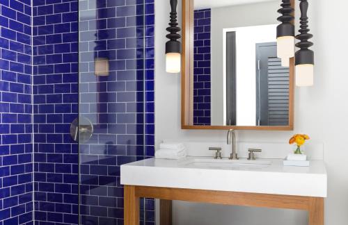 a bathroom with blue tiles and a sink and a mirror at Kimpton Angler’s Hotel South Beach by IHG in Miami Beach