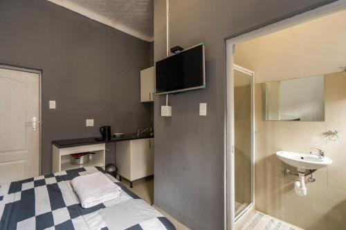 bagno con letto, lavandino e televisione di Hasate Guest House 10 Florence street Oakdale Belliville 7530 cape town south African a Città del Capo