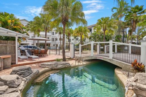 a bridge over a pool with palm trees at Royal Palm Villas in Cairns