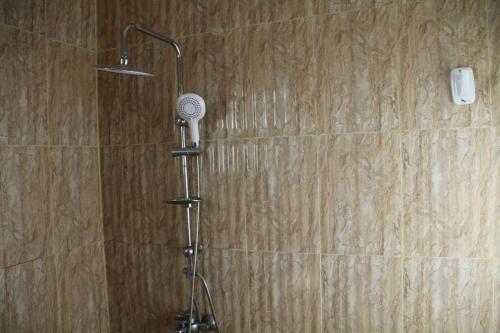 a shower with a shower head in a bathroom at The Pearl Farm Chalet in Barka