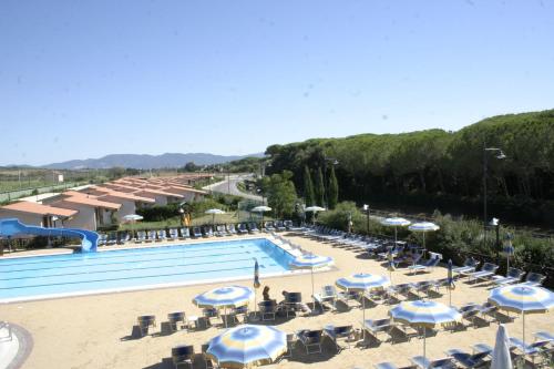 a swimming pool with umbrellas and chairs and a resort at Villaggio Il Girasole in Follonica