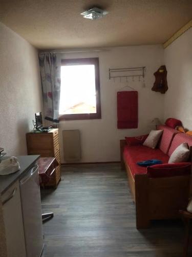 a living room with a red couch and a window at Les studios du chalet club Valfréjus in Modane