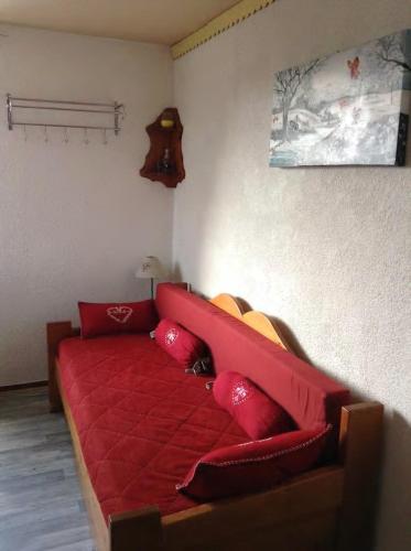 a red couch with red pillows in a room at Les studios du chalet club Valfréjus in Modane