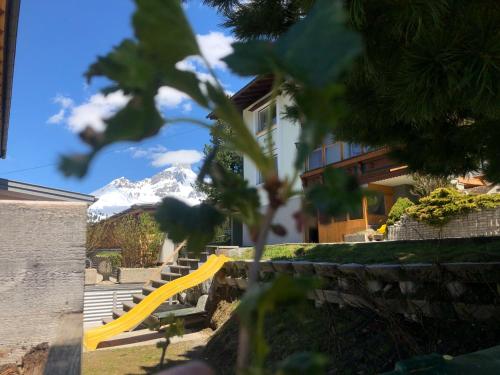a yellow slide in a yard with a snow covered mountain at Haus Waldrast in Filzmoos