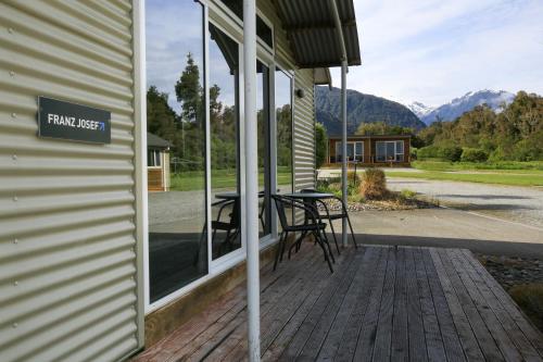 a porch with a table and a sign on the side of a house at Franz Alpine Retreat in Franz Josef